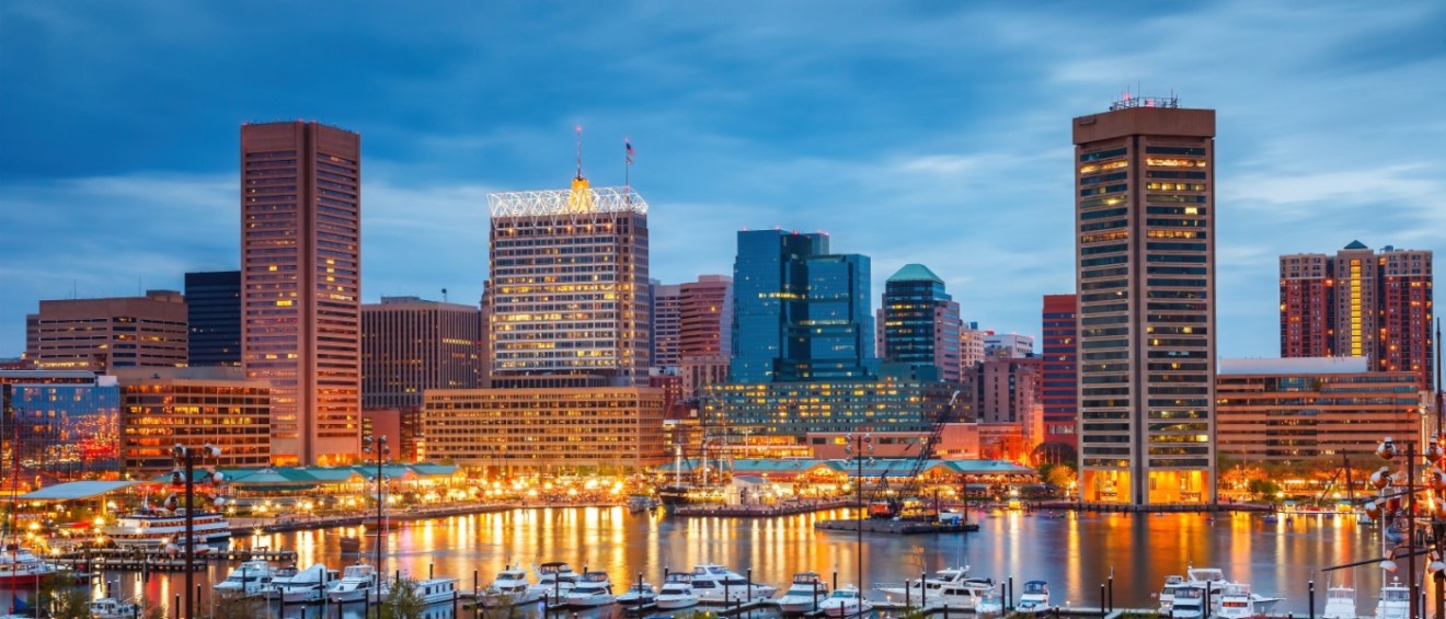 Skyline of Baltimore at dusk, with plenty of illuminated skyscrapers, as seen from the city’s inner harbor.