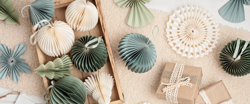 A collection of Scandinavian-style Christmas paper honeycomb ornaments neatly arranged in a box, accompanied by simple, beautifully wrapped gifts.