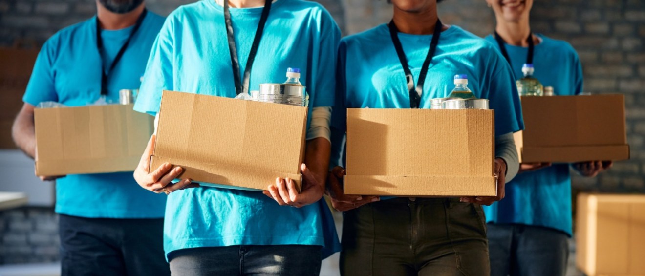Team of volunteers with donated food in cardboard boxes at charitable foundation.