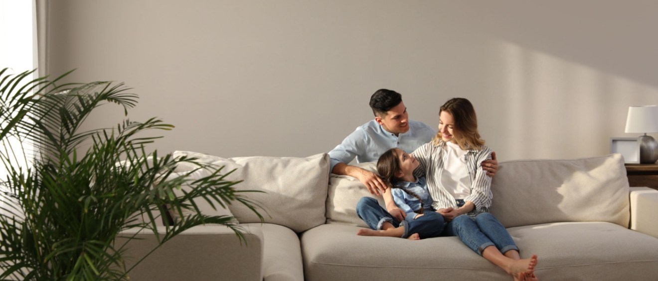 Family with little daughter resting on sofa in living room of a family-friendly apartment.