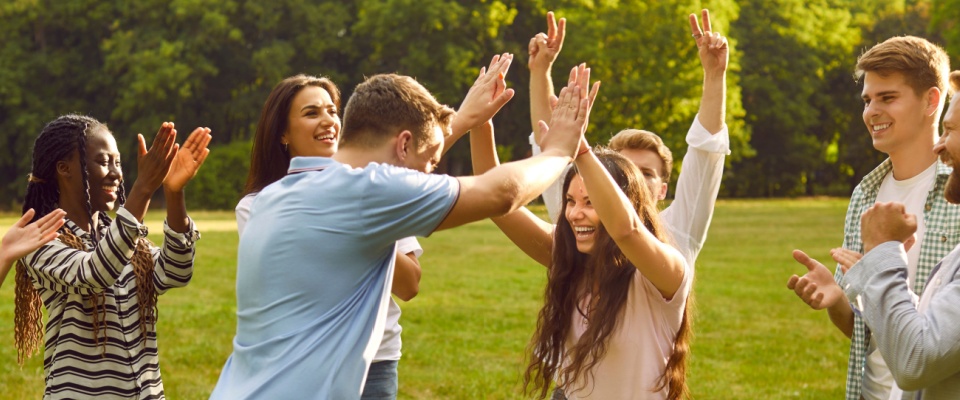 A joyful group of diverse people celebrating a victory in an outdoor team game in a lush green summer park. 