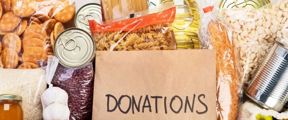 An assortment of food donations arranged on a light background, viewed from above. 