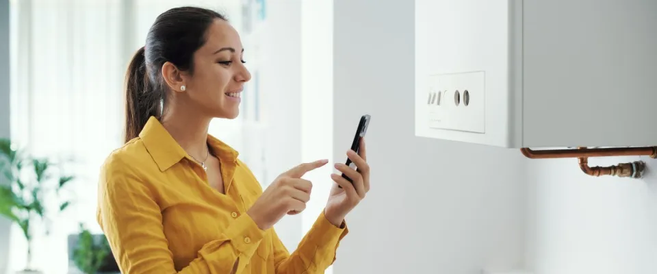 Woman managing and programming her smart boiler using her smartphone.