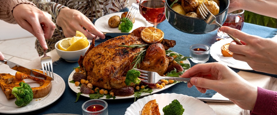 A group of people enjoying a typical Thanksgiving dinner, with a large roast turkey in the middle of the table.
