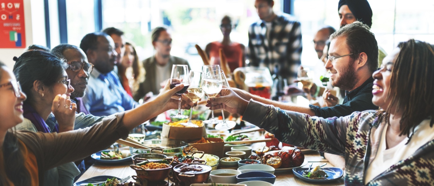 A group of people raising their glasses in a cheerful toast, smiling and celebrating together.