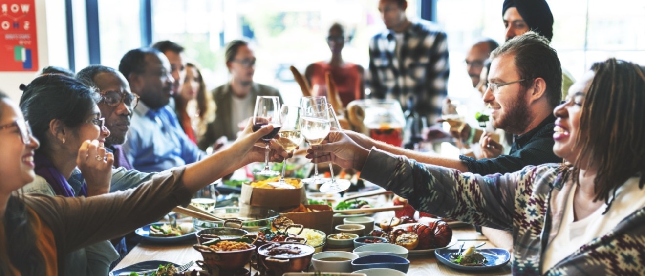 A group of people raising their glasses in a cheerful toast, smiling and celebrating together.