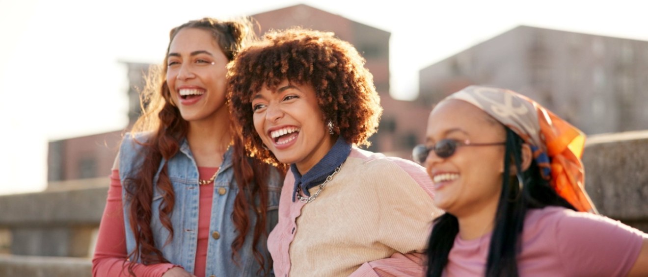 Three Gen Z friends smiling and enjoying city life together.