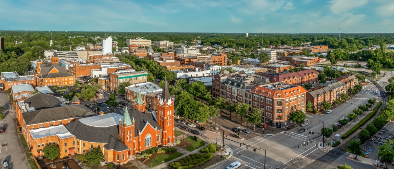 Aerial view of downtown Fayetteville, NC, showcasing historic buildings and tree-lined streets. Renters can find affordable neighborhoods in Fayetteville, NC.