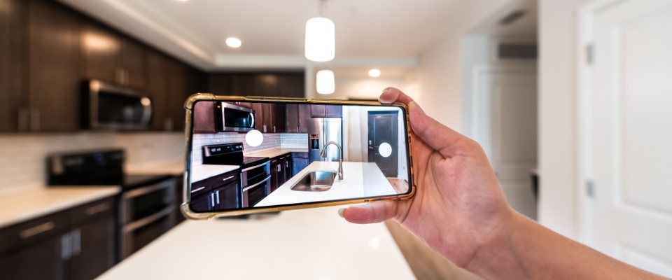 A close-up of a person’s hand, holding a smartphone while taking photos of an apartment, for the purposes of a virtual tour of that property.