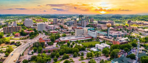 An aerial view of Knoxville, TN, with its skyscraper-filled downtown area pictured at sundown.