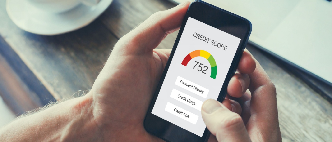 A person holding their mobile phone, which is displaying a credit score inside an application that checks credit history.