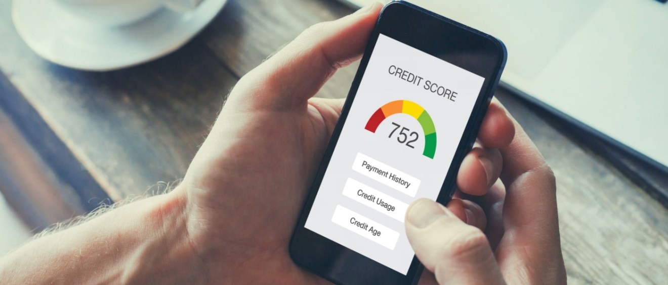 A person holding their mobile phone, which is displaying a credit score inside an application that checks credit history.