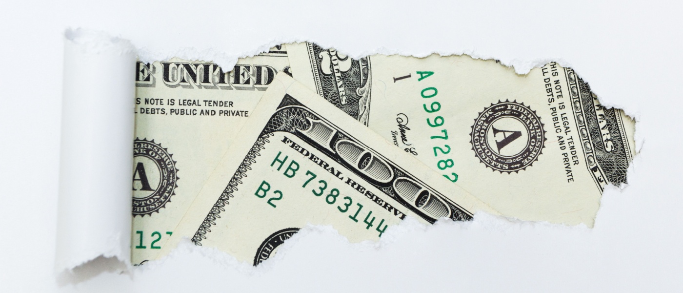 Torn paper revealing a close-up of dollar bills, symbolizing the hidden costs of renting an apartment.