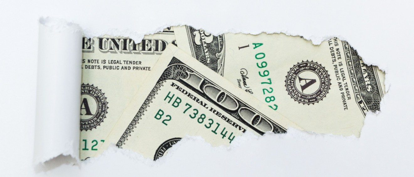 Torn paper revealing a close-up of dollar bills, symbolizing the hidden costs of renting an apartment.