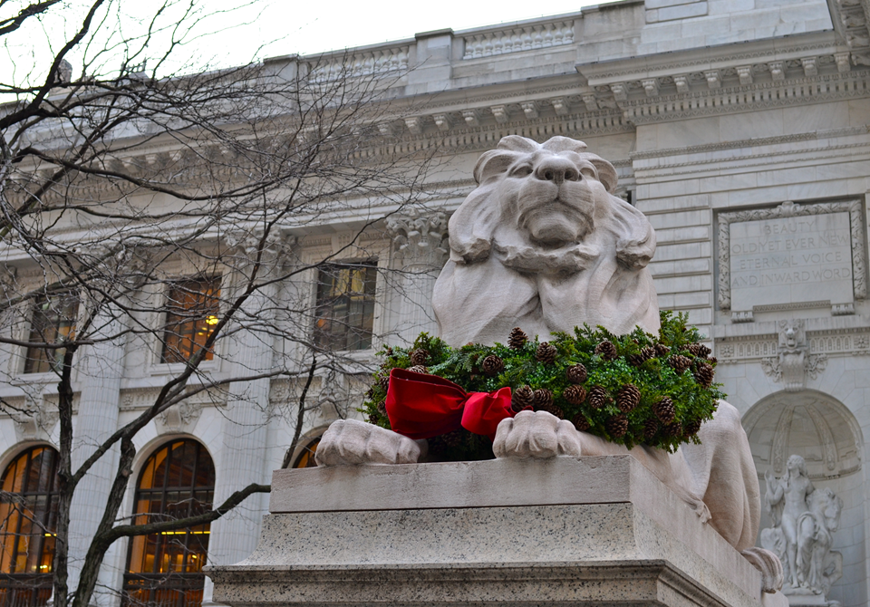 view of lion in front of nyc public library on 5th avenue decorated for holidays