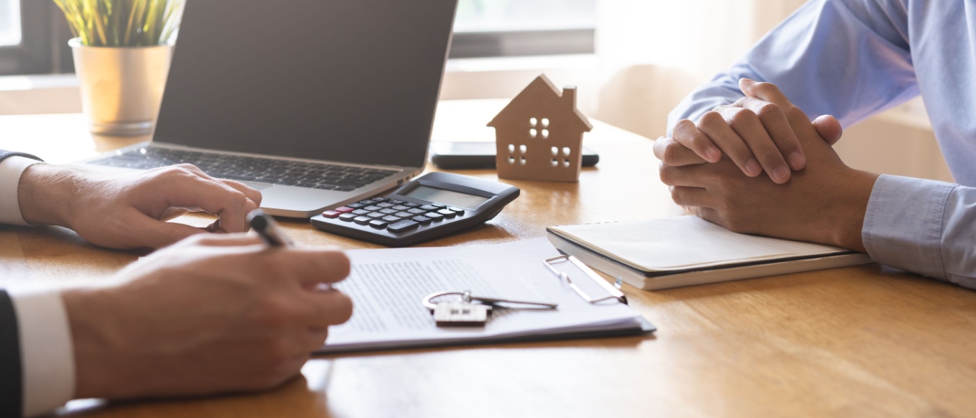 A man signing a rental or purchase contract for a home or apartment with a landlord or realtor. The scene reflects a successful mortgage or loan agreement, symbolizing property lease or ownership, and showcases a professional and satisfied interaction in a real estate setting.
