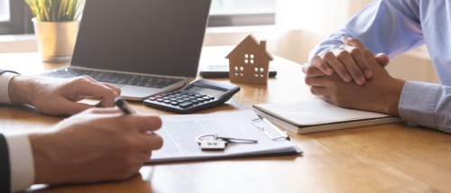 A man signing a rental or purchase contract for a home or apartment with a landlord or realtor. The scene reflects a successful mortgage or loan agreement, symbolizing property lease or ownership, and showcases a professional and satisfied interaction in a real estate setting.