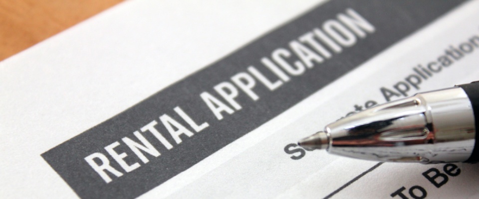 A close-up of a rental application form, with a shiny ballpoint pen sitting on top of it.