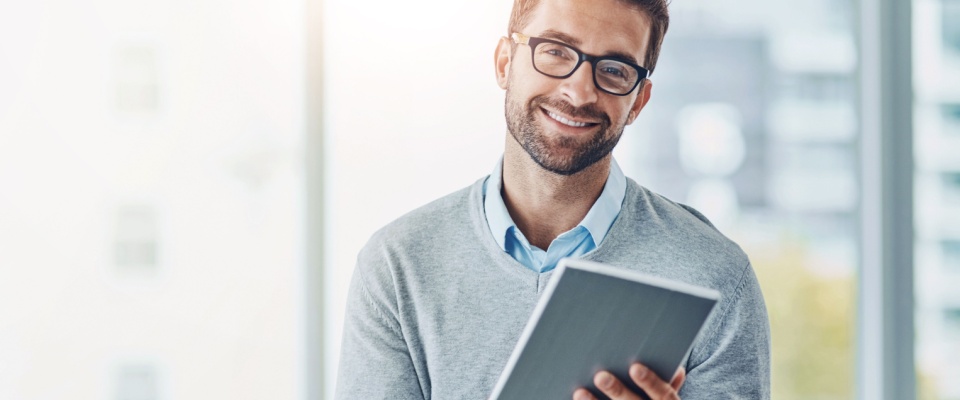 A portrait of a smiling businessman wearing glasses, holding a tablet in an office setting. He is engaged in tasks such as managing schedules, emails, and financial administration. The scene highlights his role as an accountant or professional handling calendar checks, investments, and tax compliance using modern technology.