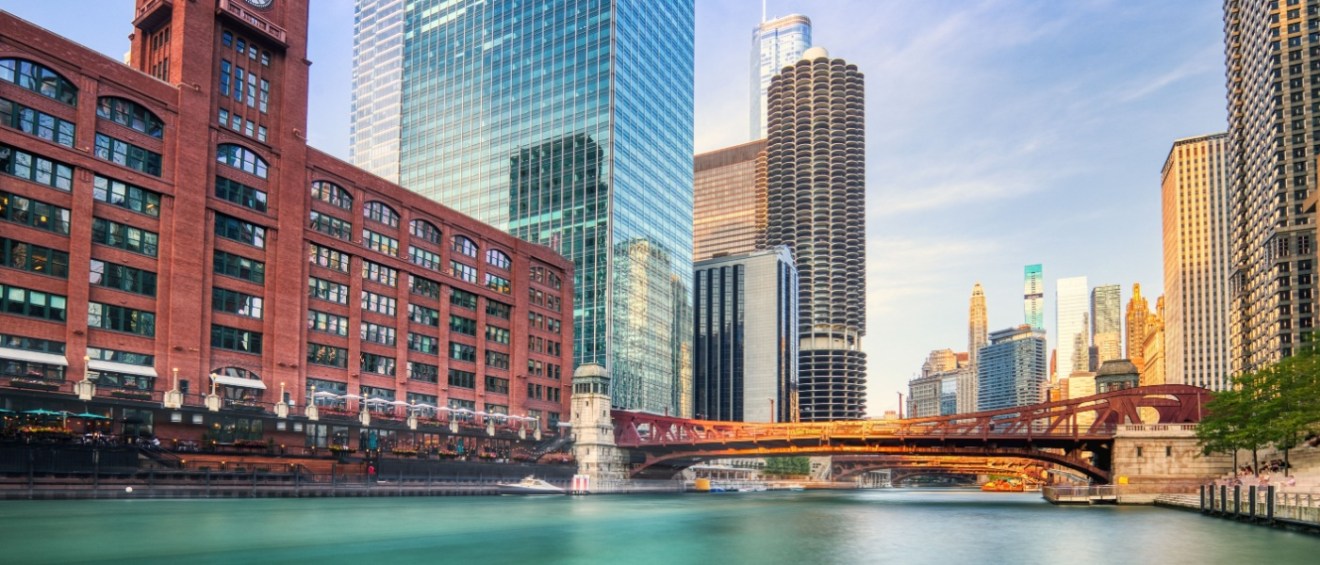 A stunning view of downtown Chicago at sunset, showcasing the iconic cityscape with modern skyscrapers reflecting in the waters of the Chicago River.