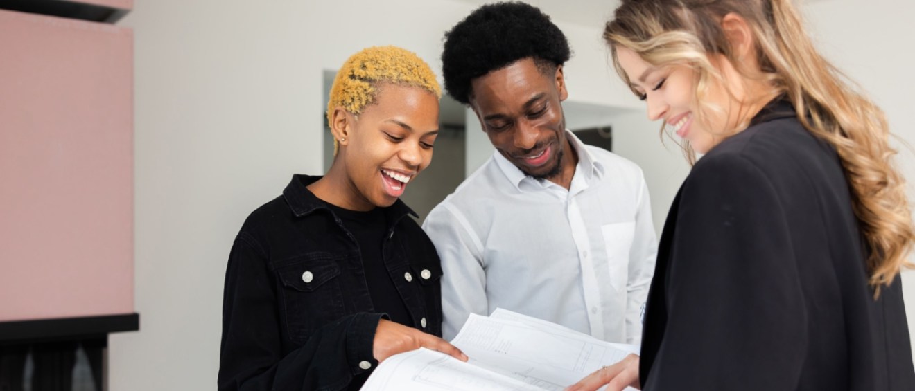 Couple touring a modern apartment complex with a blonde realtor highlighting the features and amenities.