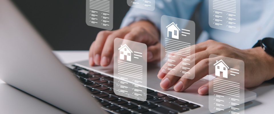 A person's hands typing on a laptop with virtual apartment listings icons, representing the concept of online apartment searches.