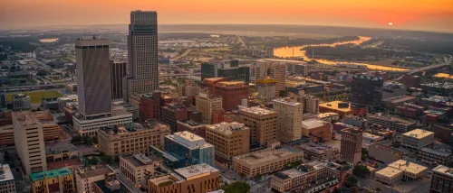 An aerial view of the downtown area in Omaha, pictured at sunset, with its buildings set against an orange sky.