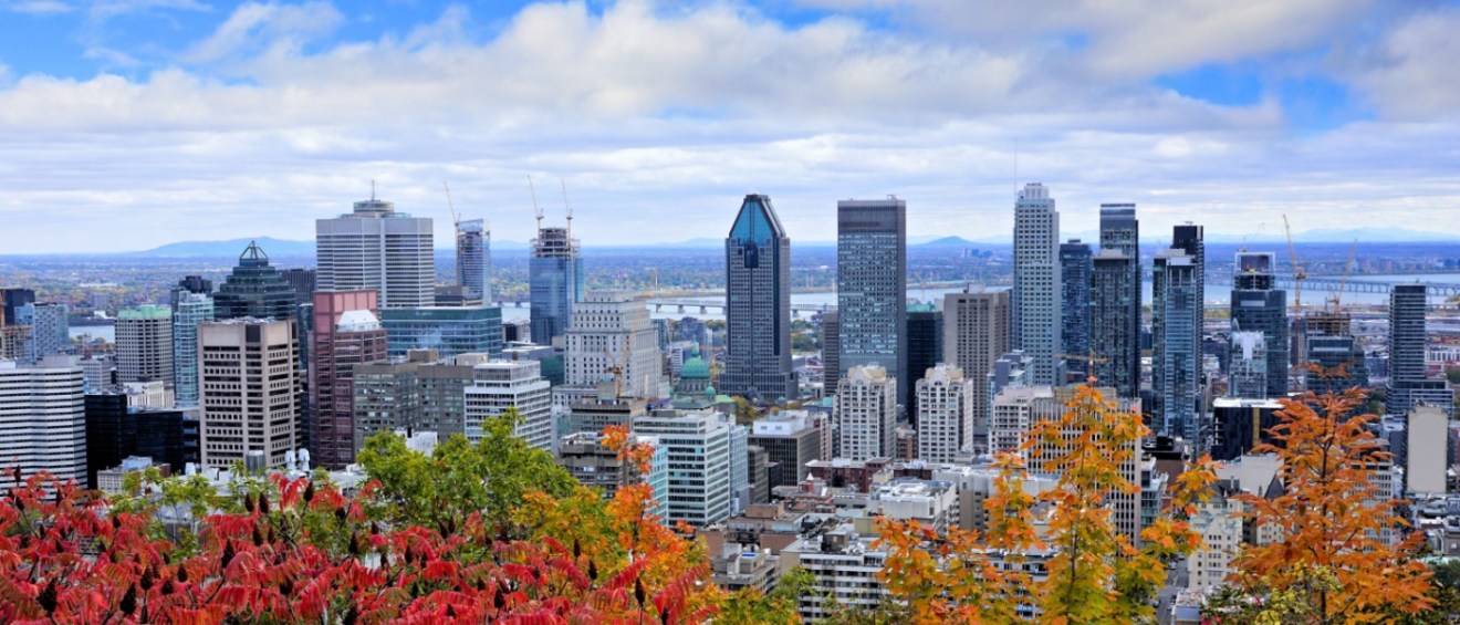 A vibrant skyline view of downtown Montreal, Canada, framed by autumn foliage.