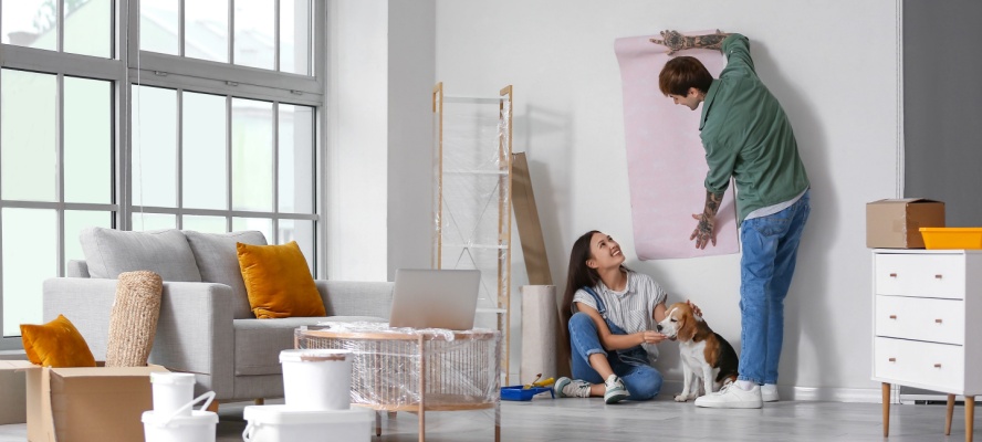 Young couple with Beagle dog wallpapering during home renovations