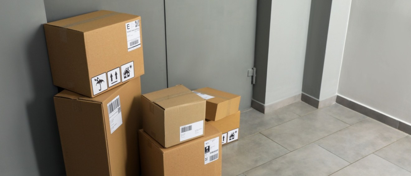 A stack of boxes, piled one on top of the other, near the inner entrance of an apartment complex.