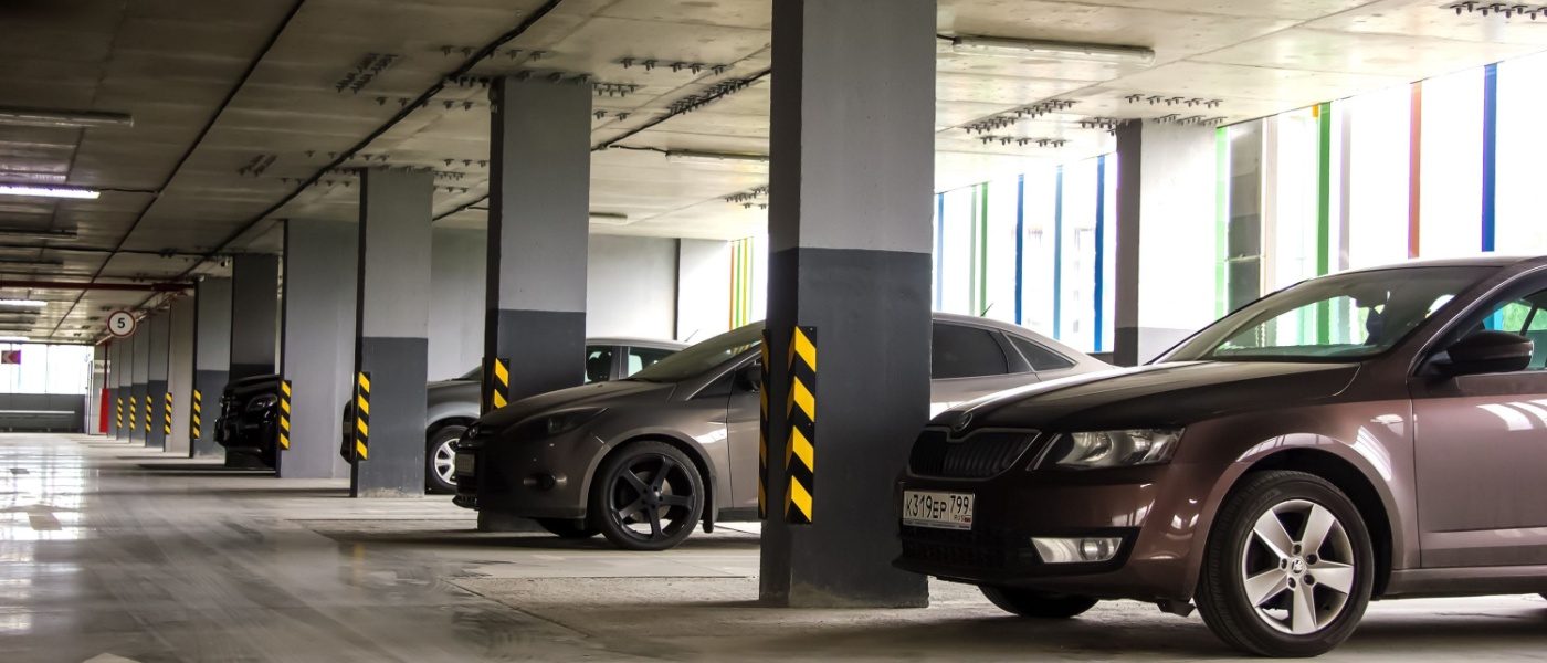 An underground parking lot beneath a residential building, pictured during the day, with four different cars being visible in this angle.
