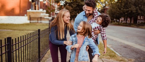 Smiling young family walking together outdoors, happy that they found the best family neighborhood for them.