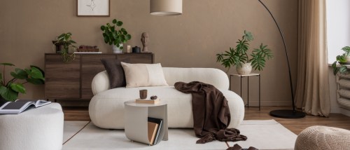 A stylish living room featuring a curved sofa, modern art on the walls, and a large floor lamp.