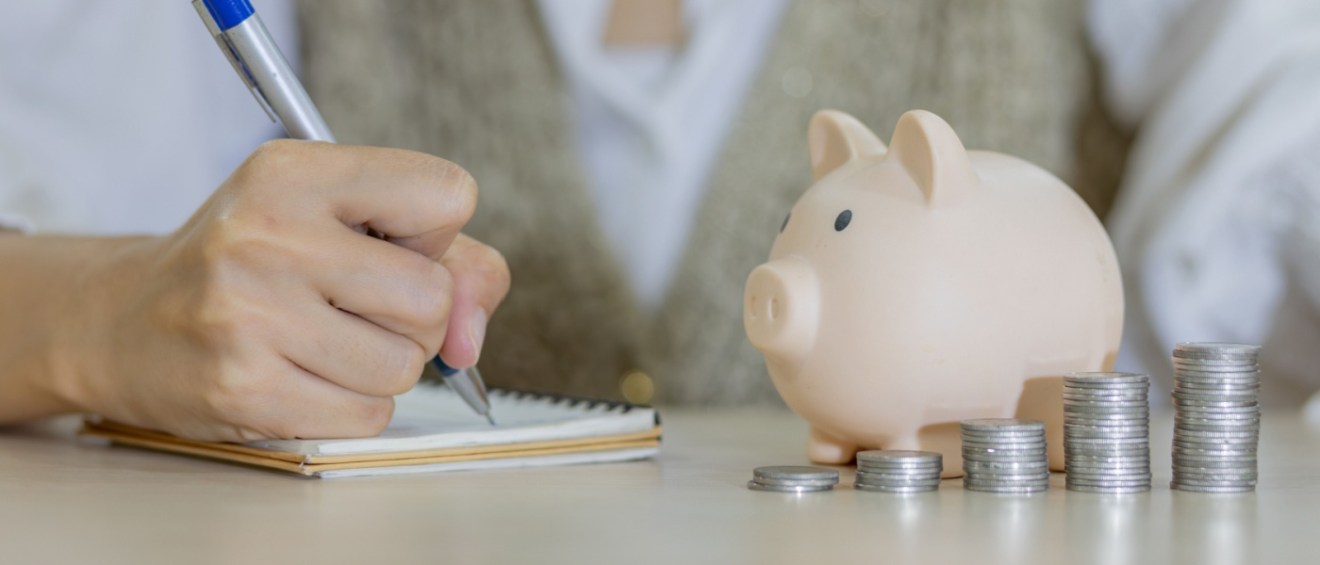 Discover the concept of saving money with a woman’s hand placing coins into a piggy bank, symbolizing wealth and financial growth.