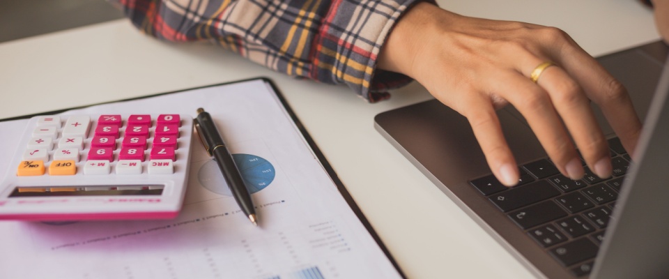 Businessman reviewing financial graphs and reports at an office desk, analyzing costs and investment data as part of financial planning and management.