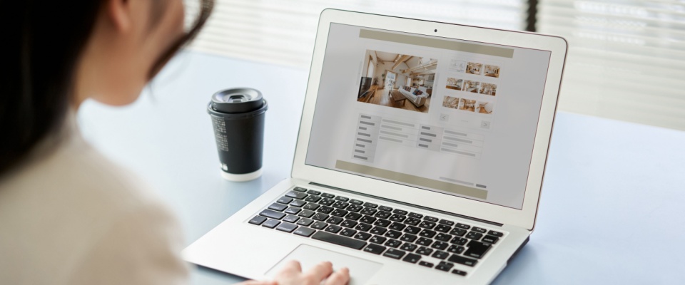 A woman browsing real estate websites on a computer, exploring property options and housing opportunities related to student loans.