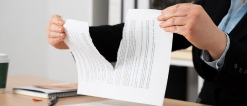A person ripping up a document, symbolizing breaking a lease before it starts and canceling a rental agreement before move-in.