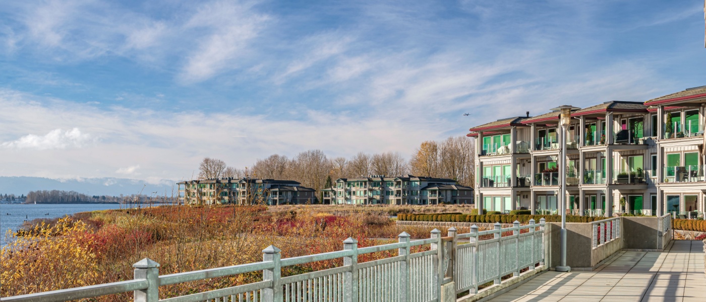 Modern waterfront apartments in Vancouver, WA, with scenic river views, a walking path, and lush autumn foliage. Find affordable neighborhoods in Vancouver WA.