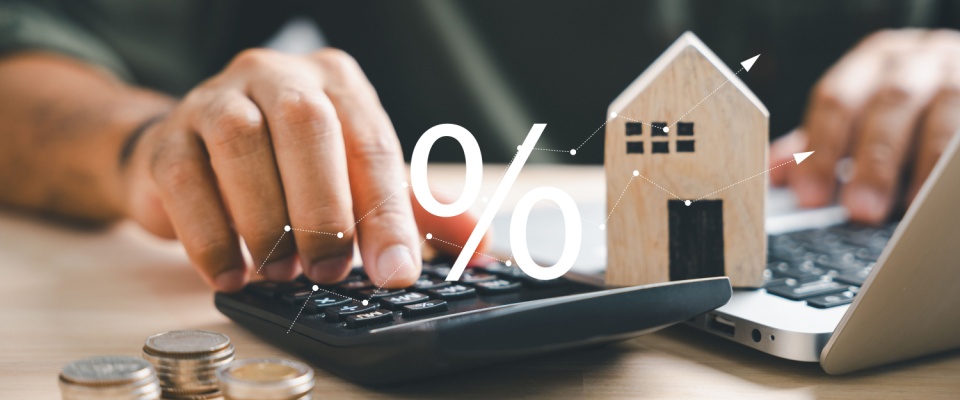 A landlord managing their duties by using a laptop and calculator to handle finances, with a small stack of coins beside them.