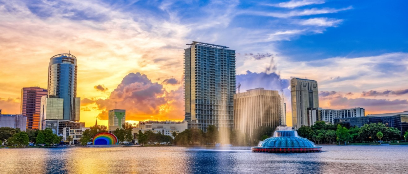 A beautiful sunset over the Orlando skyline and the fountain at Lake Eola Park, showcasing the city's charm and affordable neighborhoods.