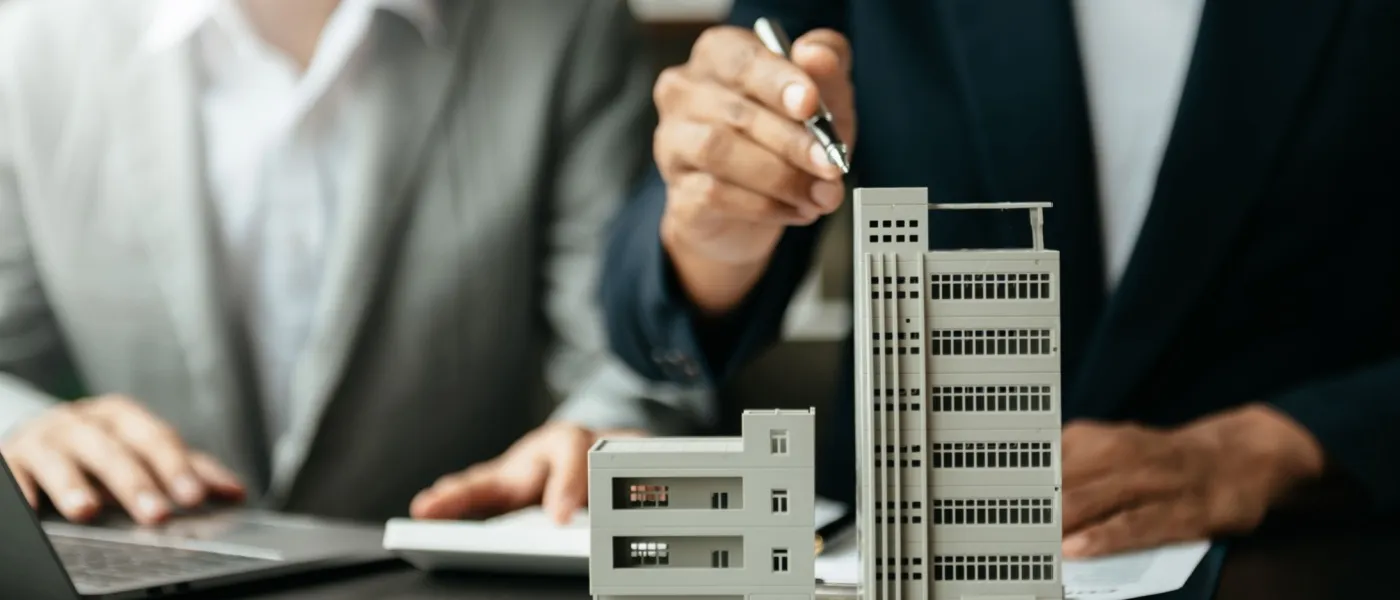 Close-up of apartment buildings models and two people sitting at a desk, discussing renter rights.
