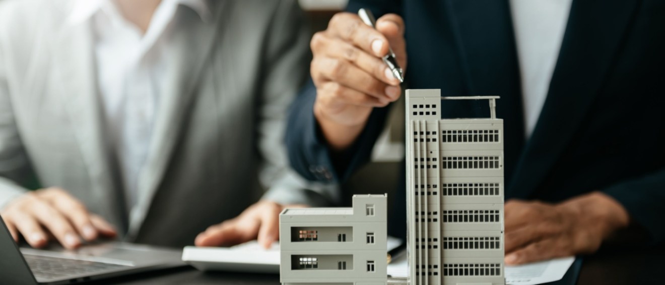 Close-up of apartment buildings models and two people sitting at a desk, discussing renter rights.