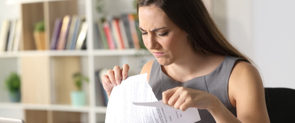 A person ripping up a document in frustration, symbolizing breaking a lease before it starts.