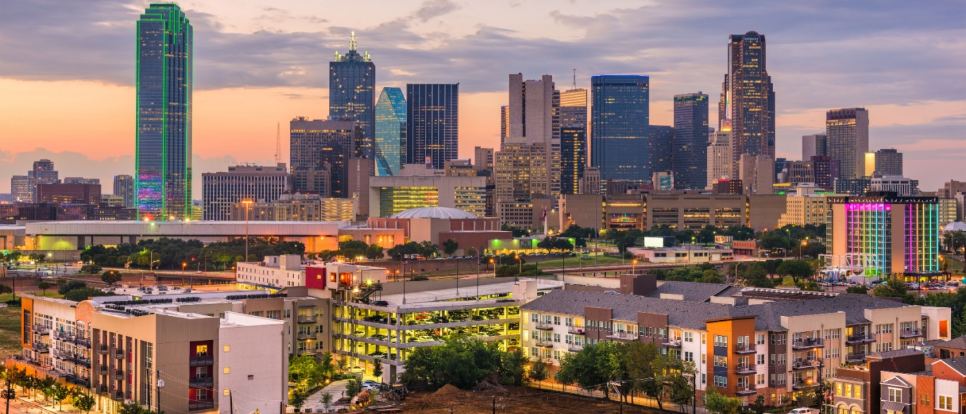 Dallas skyline glowing at twilight with prominent skyscrapers and lower-rise apartment buildings, showcasing the cityscape relevant to renters assessing the cost of living in Dallas.