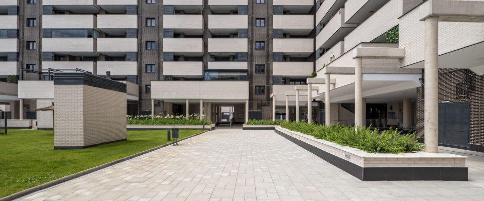 Common areas of a residential urbanization featuring lawned gardens, walkways, and large planters, highlighting well-maintained shared spaces that are a result of common area maintenance fees.