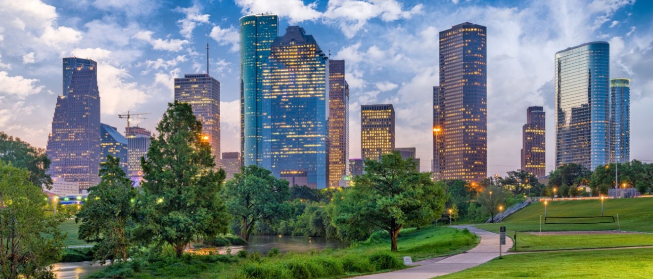 The skyline of downtown Houston, Texas, with trees and green spaces in front to illustrate the most affordable neighborhoods for renters.