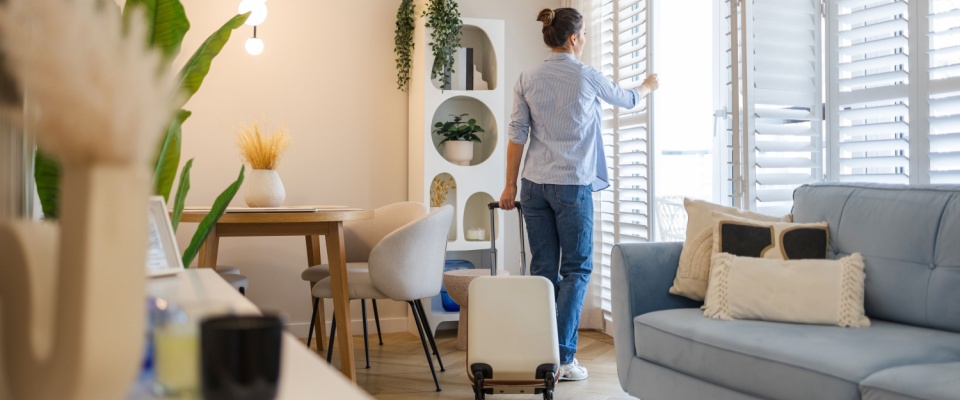 Young woman with her suitcase in a rented apartment, capturing the excitement of moving in and finding a great deal on a rental.