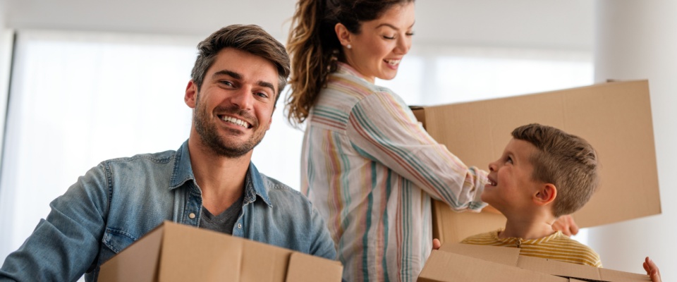 Happy family with cardboard boxes in their new home on moving day, capturing the joy of a fresh start and the success of finding a great deal on a rental.