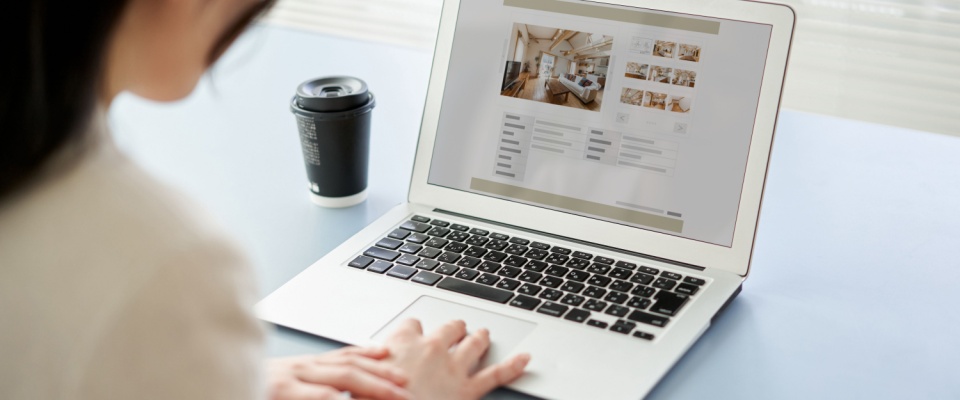 Young woman viewing real estate websites on a computer, actively engaged in an apartment search and exploring housing options online.