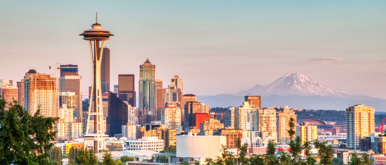 Cityscape of Seattle at sunset, featuring high-rise apartment buildings and iconic landmarks, used to support a renter’s guide on 5 key questions to ask before signing a lease in the city.